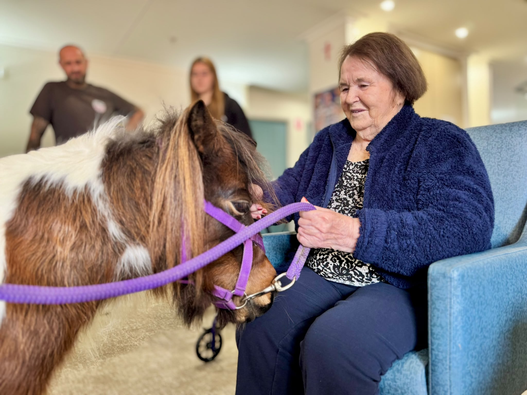 An aged-care resident enjoying a cuddle with Peanut
